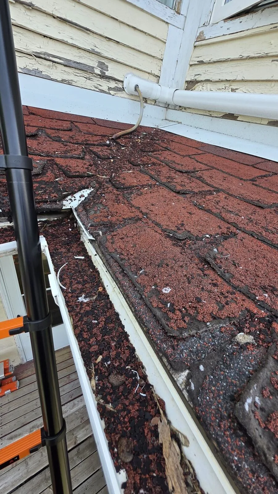 Worn curling shingles at the eave